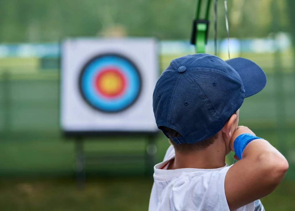 A kid aiming at the dartboard