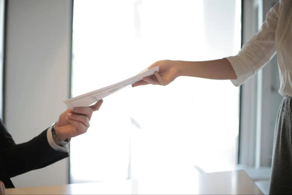 A candidate handing over her resume to the hiring manager