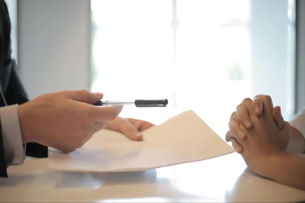 Man giving a document to sign to another person