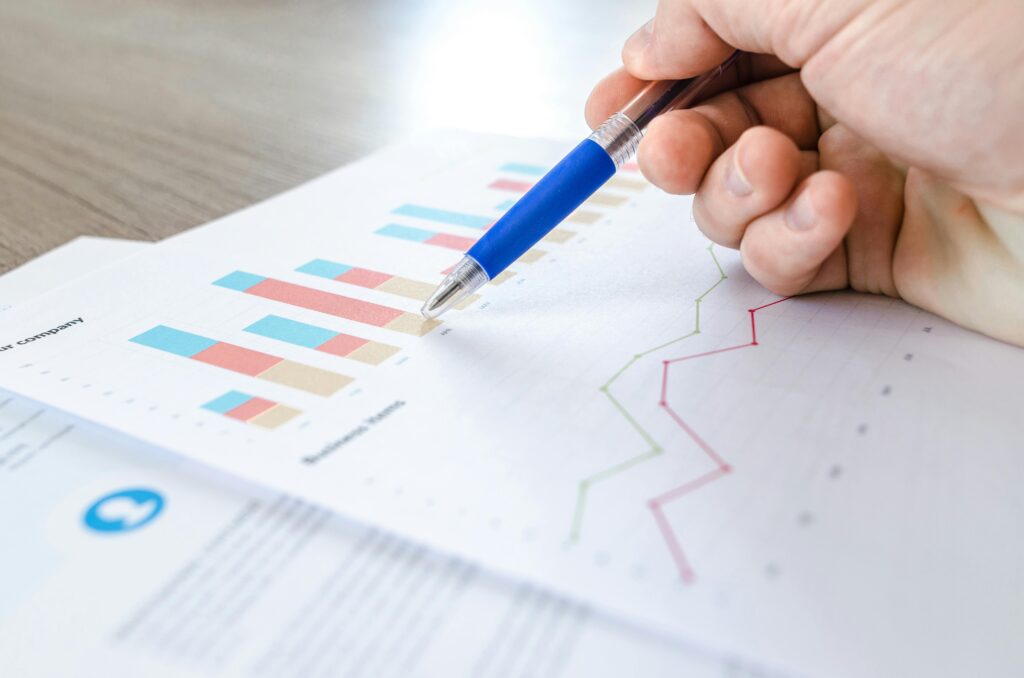 Man holding a pen pointing towards a bar graph on the report