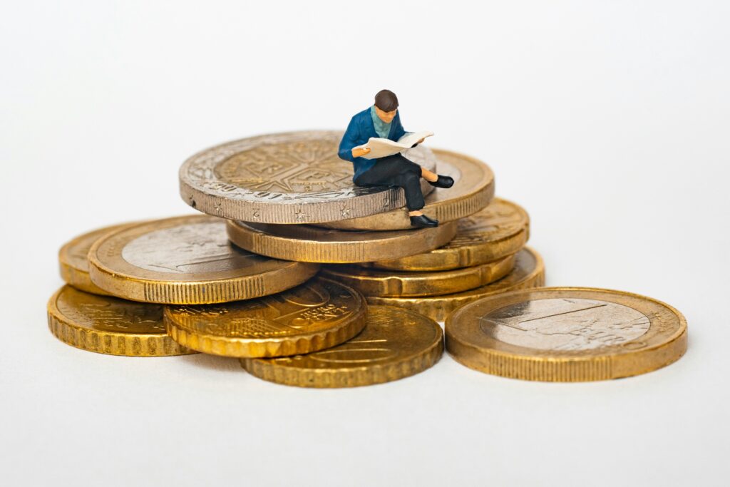 A graphic of a man sitting on the coin and reading a book